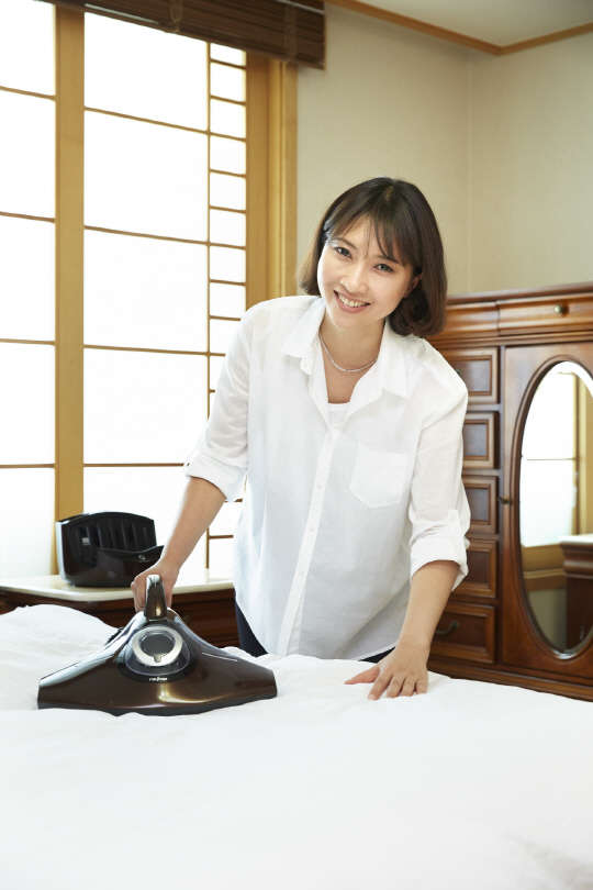 모델이 레이캅코리아의 침구청소기 레이캅RS를 사용해 침대 먼지를 제거하고 있다.  레이캅코리아 제공